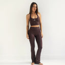 Woman wearing a brown sports bra and leggings on a white background